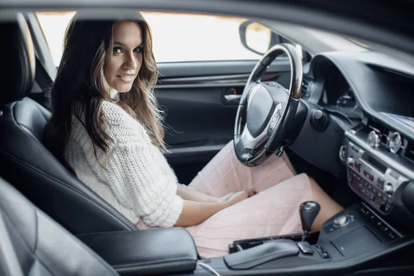 Portrait d'une jeune femme assise dans une voiture avec volant — Photo