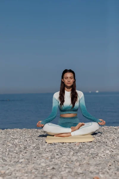 Caucasian young woman practicing yoga at seashore — Stock Photo, Image