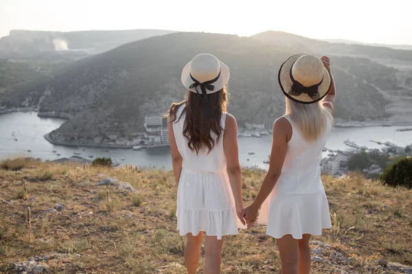 2つの幸せな友人、観光コンセプト夏休み。ドレスと帽子の親友。手によって道を示す — ストック写真