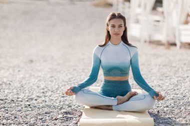 Kafkasyalı genç kadın deniz kıyısında yoga yapıyor.