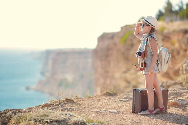 Viajera niña. viaje solo. chica caminando con cámara y maleta en la naturaleza por mar. viajes, vacaciones, vacaciones — Foto de Stock