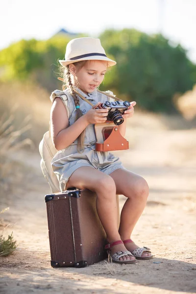 Child girl traveler. trip alone. girl walking with camera and suitcase on nature by sea. travel, vacation, holidays — Stock Photo, Image