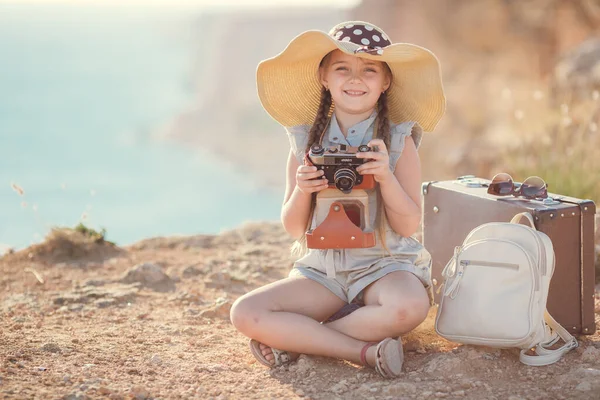 Viaggiatrice bambina. viaggio da solo. ragazza che cammina con macchina fotografica e valigia sulla natura via mare. viaggi, vacanze, vacanze — Foto Stock