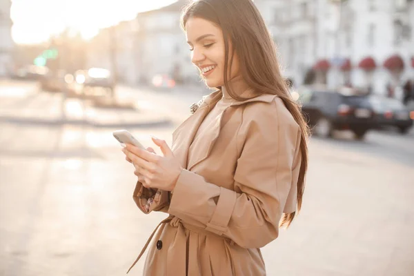 Happy woman with phone outdoors typing message — Stock Photo, Image