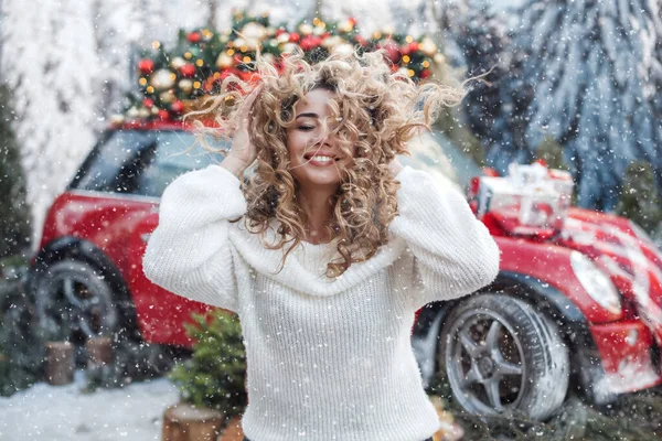 Pretty blonde woman having ful outdoors in winter snowy weather. witg red car on background. happy smiling — Stock Photo, Image