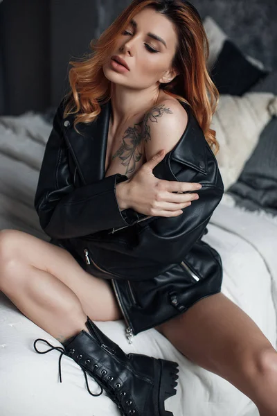 Pretty sexy woman posing in studio in black leather jacket and boots — Stock Photo, Image