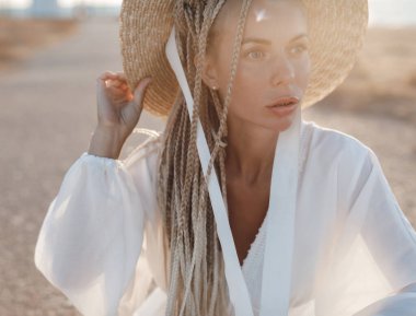 Açık havada şapkası ve çantası olan mutlu genç bir kadının yakın plan portresi.