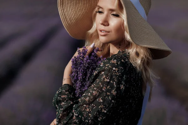 Fashion portrait of a pretty young woman in lavender field in hat with bag — Stock Photo, Image