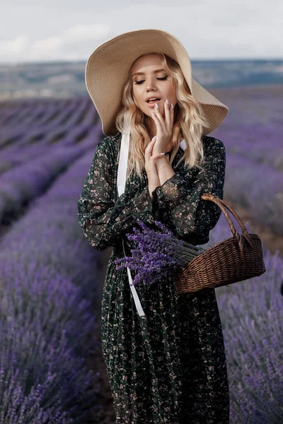 Retrato de moda de una bonita joven en el campo de lavanda en sombrero con bolsa —  Fotos de Stock