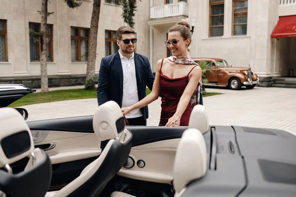 Casal de moda de homem e mulher com carro cabrio — Fotografia de Stock