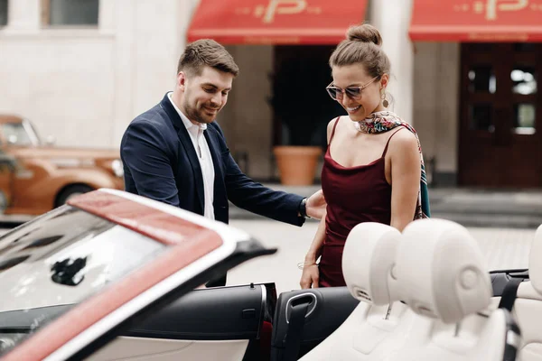 Casal de moda de homem e mulher com carro cabrio — Fotografia de Stock