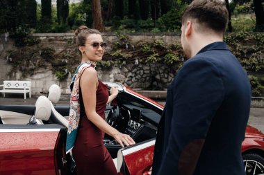Cabrio arabası olan iki kadın ve erkek.