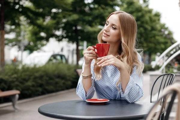 Mujer joven y tranquila con café en la cafetería al aire libre en la ciudad — Foto de Stock