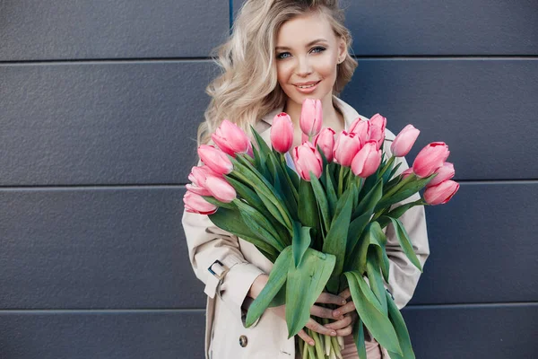 Vacker blond kvinna med blommor tulpaner utomhus — Stockfoto