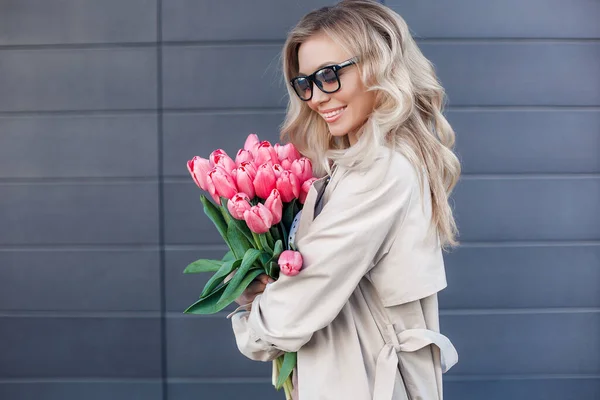 Vacker blond kvinna med blommor tulpaner utomhus — Stockfoto