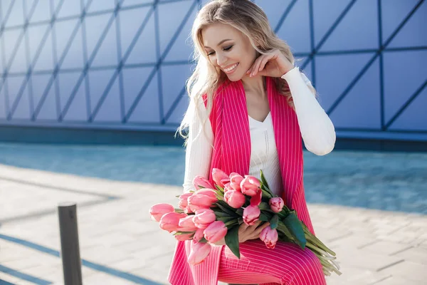 Vacker blond kvinna med blommor tulpaner utomhus — Stockfoto