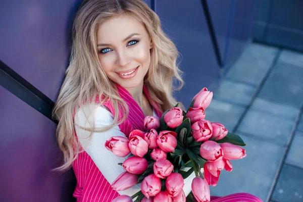 Vacker blond kvinna med blommor tulpaner utomhus — Stockfoto