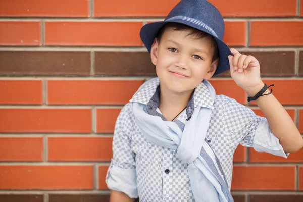 Stylischer Junge mit Hut posiert auf einer Ziegelwand — Stockfoto