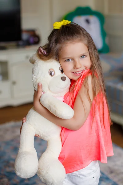 A small beautiful girl hugs funny bear — Stock Photo, Image