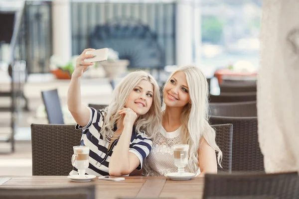 Duas meninas bebem café e usam o telefone — Fotografia de Stock