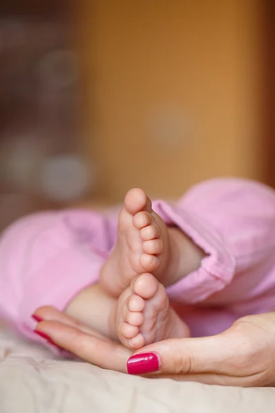 The newborn's legs in gentle hands of mother — Stock Photo, Image