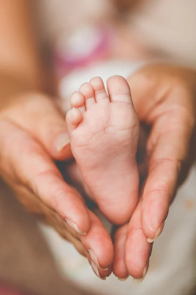 The newborn's legs in gentle hands of mother — Stock Photo, Image