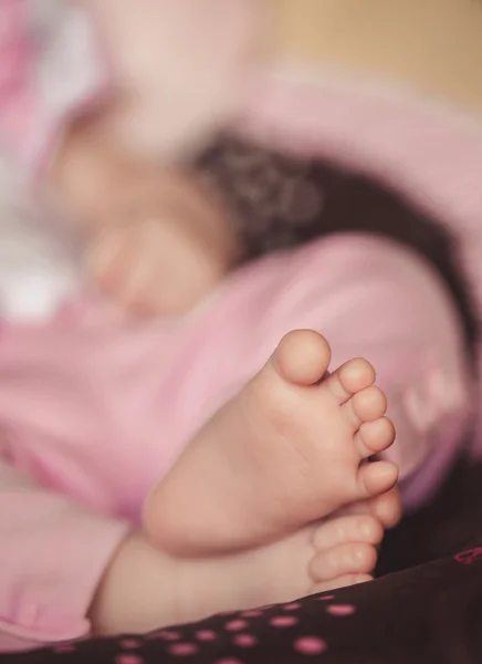 De pasgeboren baby's benen in zachte handen van moeder — Stockfoto