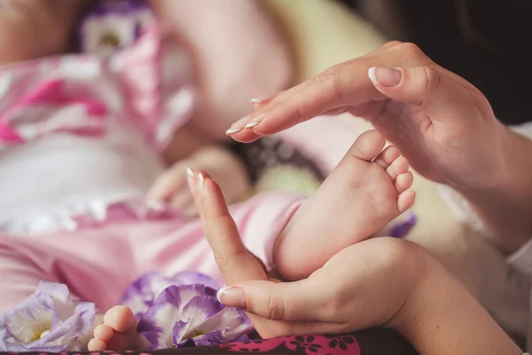 Les jambes du nouveau-né dans les mains douces de la mère — Photo