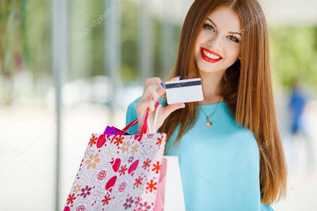 Pretty lady showing credit card in the mall