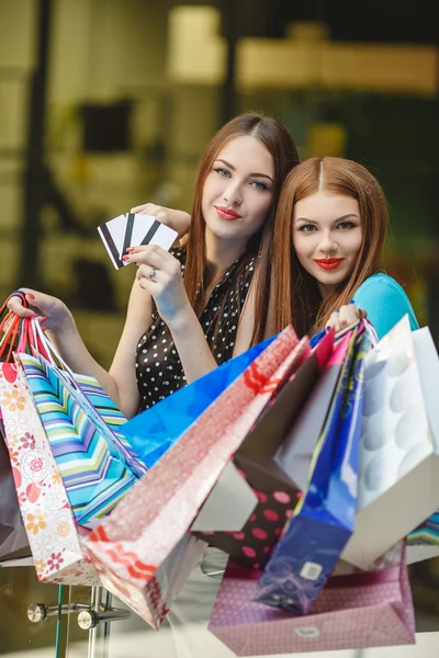 Dos mujeres hacen compras con tarjetas de crédito en el centro comercial —  Fotos de Stock