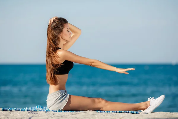 A mulher jovem move o treinamento em uma praia . — Fotografia de Stock