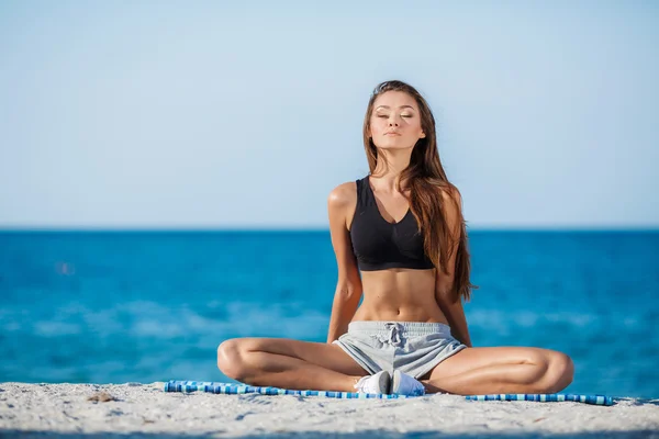 Kobieta medytuje na plaży w pobliżu morza — Zdjęcie stockowe