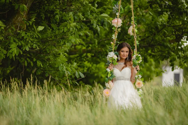 Beautiful bride is swinging on a swing — Stock Photo, Image