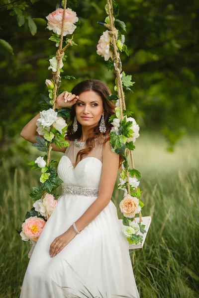 Mooie bruid is swingend op een schommel — Stockfoto