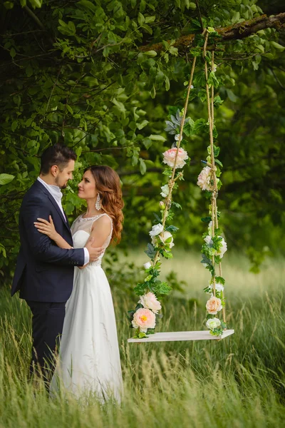 Beautiful bride with fiance is swinging on a swing — Stock Photo, Image