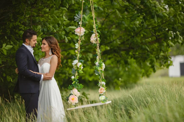 Beautiful bride with fiance is swinging on a swing — Stock Photo, Image