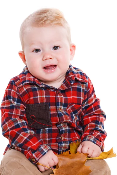 Kleine jongen spelen op de verdieping met esdoorn bladeren. — Stockfoto