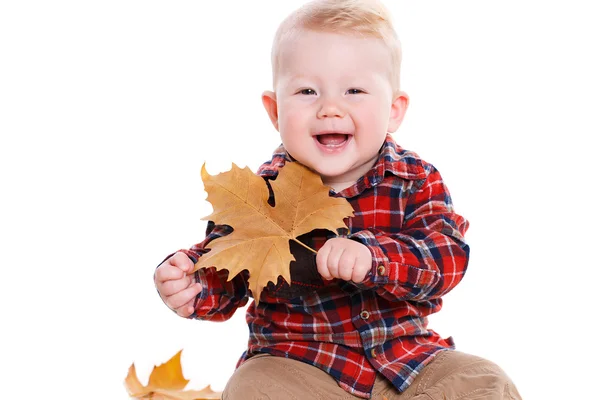 Liten pojke leker på golvet med maple lämnar. — Stockfoto