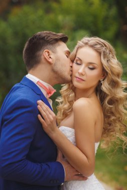 Damat gelini yeşil bir parkta yaz aylarında kisses.