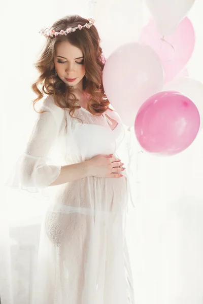 Gravid kvinna i ett vitt nattlinne med ballonger. — Stockfoto
