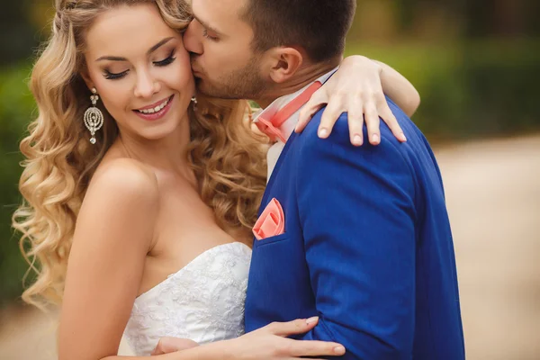 Lo sposo bacia la sposa in un parco verde in estate . — Foto Stock