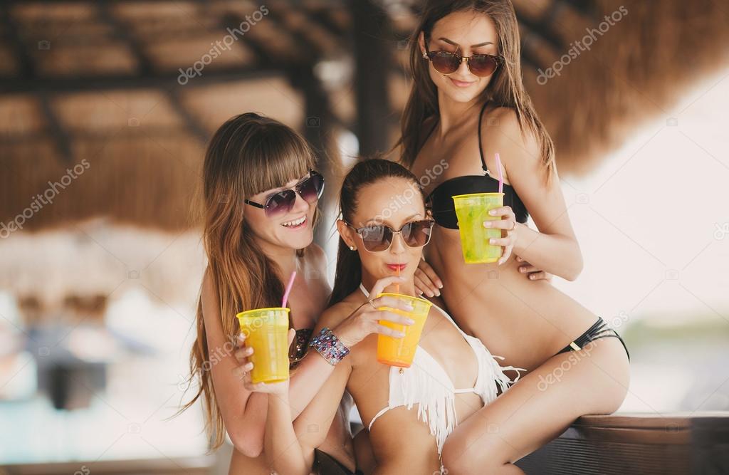 Three beautiful girls in a bar on the beach, on the ocean.