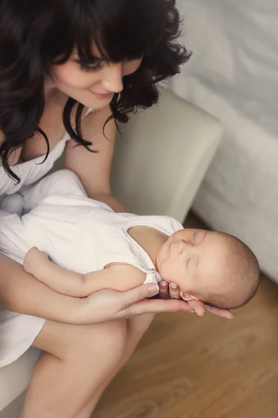 Jovem mãe com um bebê dormindo em seus braços . — Fotografia de Stock