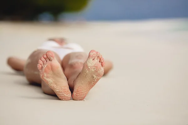 Pies de una joven en una playa de arena . — Foto de Stock