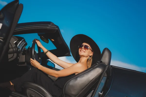 Retrato de uma jovem senhora no carro em um grande chapéu preto . — Fotografia de Stock