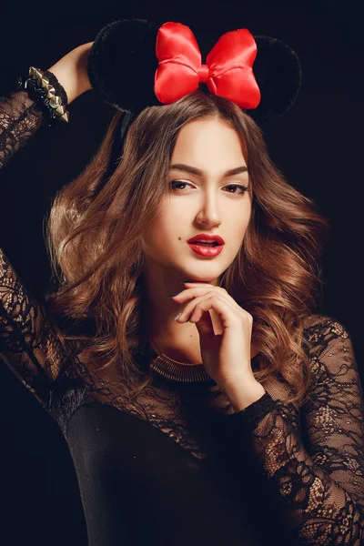 Portrait of a beautiful model with a red bow on a dark background. — Stock Photo, Image