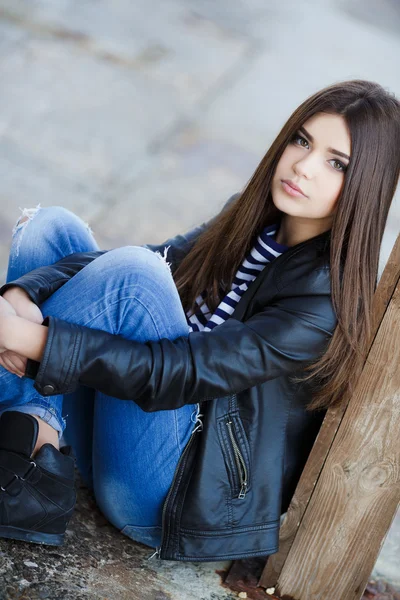 Portrait of a beautiful young woman sitting on the sidewalk. — Stock Photo, Image