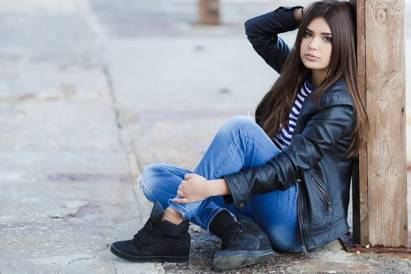 Portrait of a beautiful young woman sitting on the sidewalk. — Stock Photo, Image