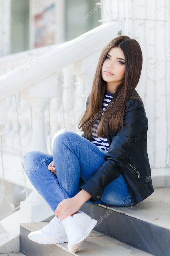 Portrait of a beautiful young woman sitting on the steps.