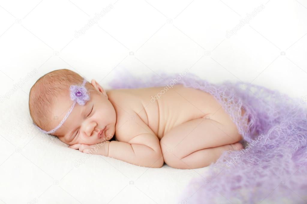 Photo of a newborn baby curled up sleeping on a blanket